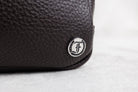 Close-up of a brown leather bag with a brand logo on a light background