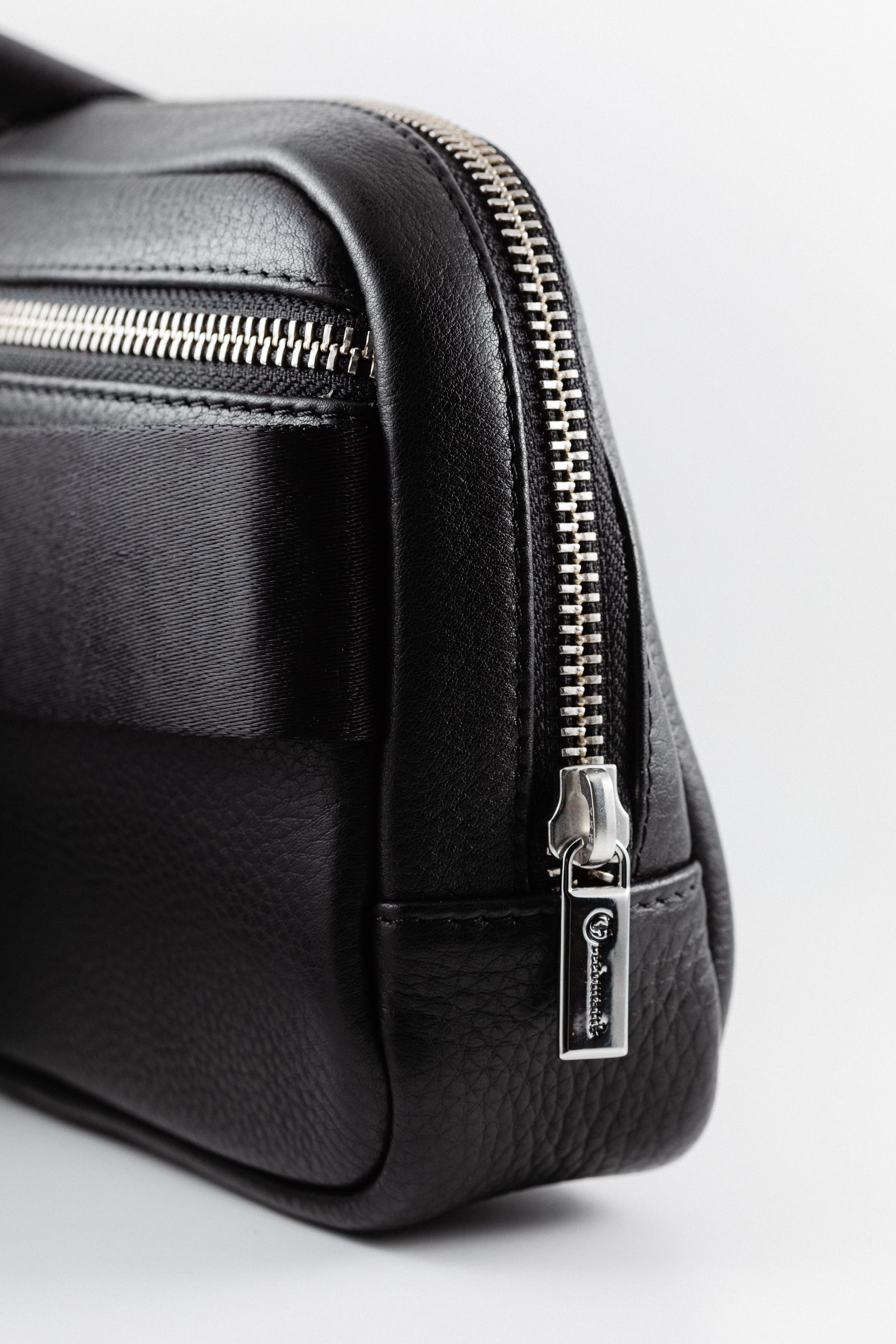 Close-up of Freedman's Norfolk Crossbody Bag in Black Leather, showing silver zipper and logo pull.