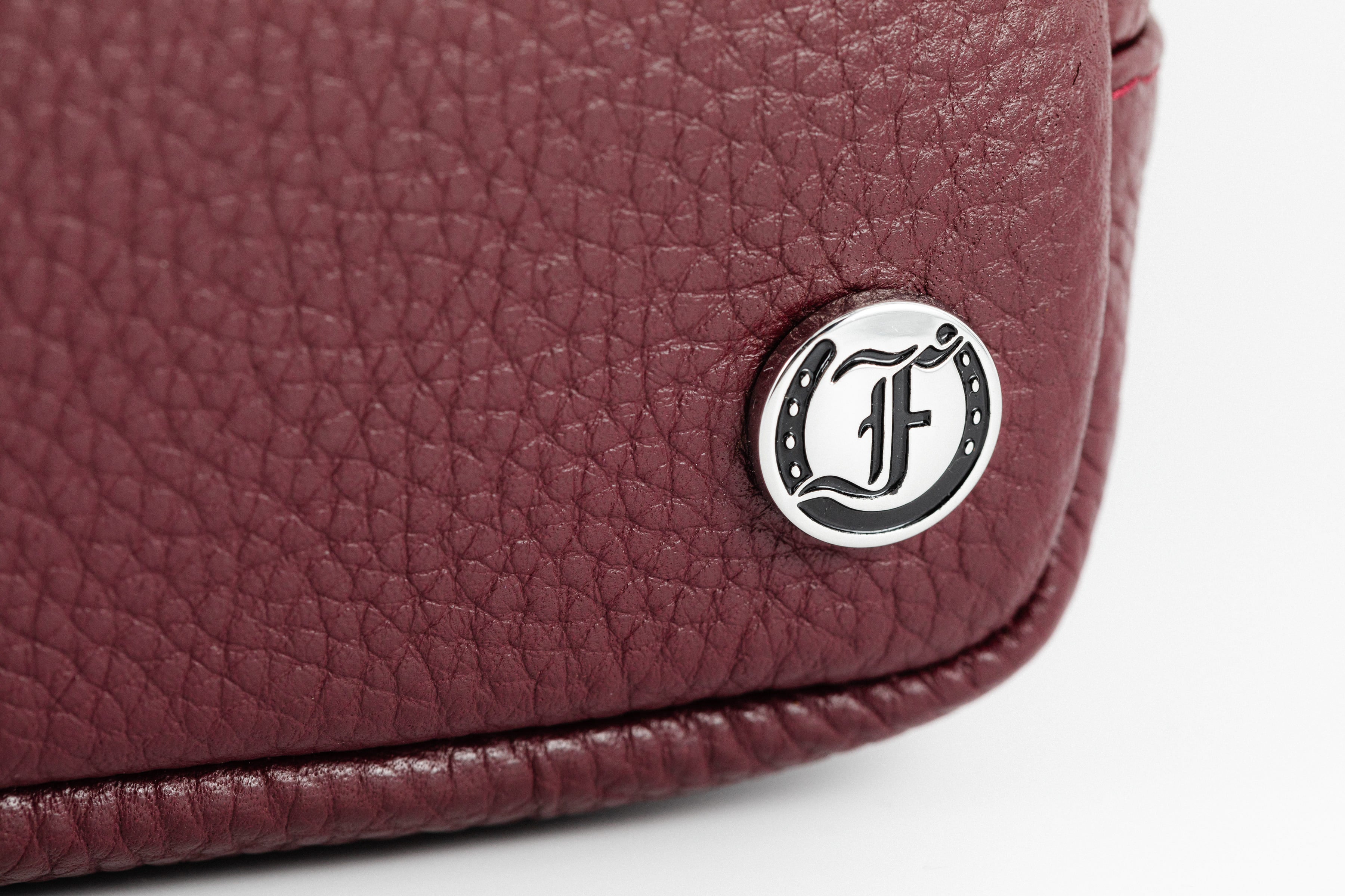 Here's an SEO-friendly alt text for the close-up image of the logo detail on the Burgundy Leather Norfolk Crossbody Bag:

Close-up of Freedman's Norfolk Crossbody Bag in Burgundy Leather, showing Freedman's silver logo medallion on textured leather.