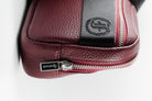 Close-up of Freedman's Norfolk Crossbody Bag in Burgundy Leather, showing silver zipper, logo pull, and branded fabric strap.
