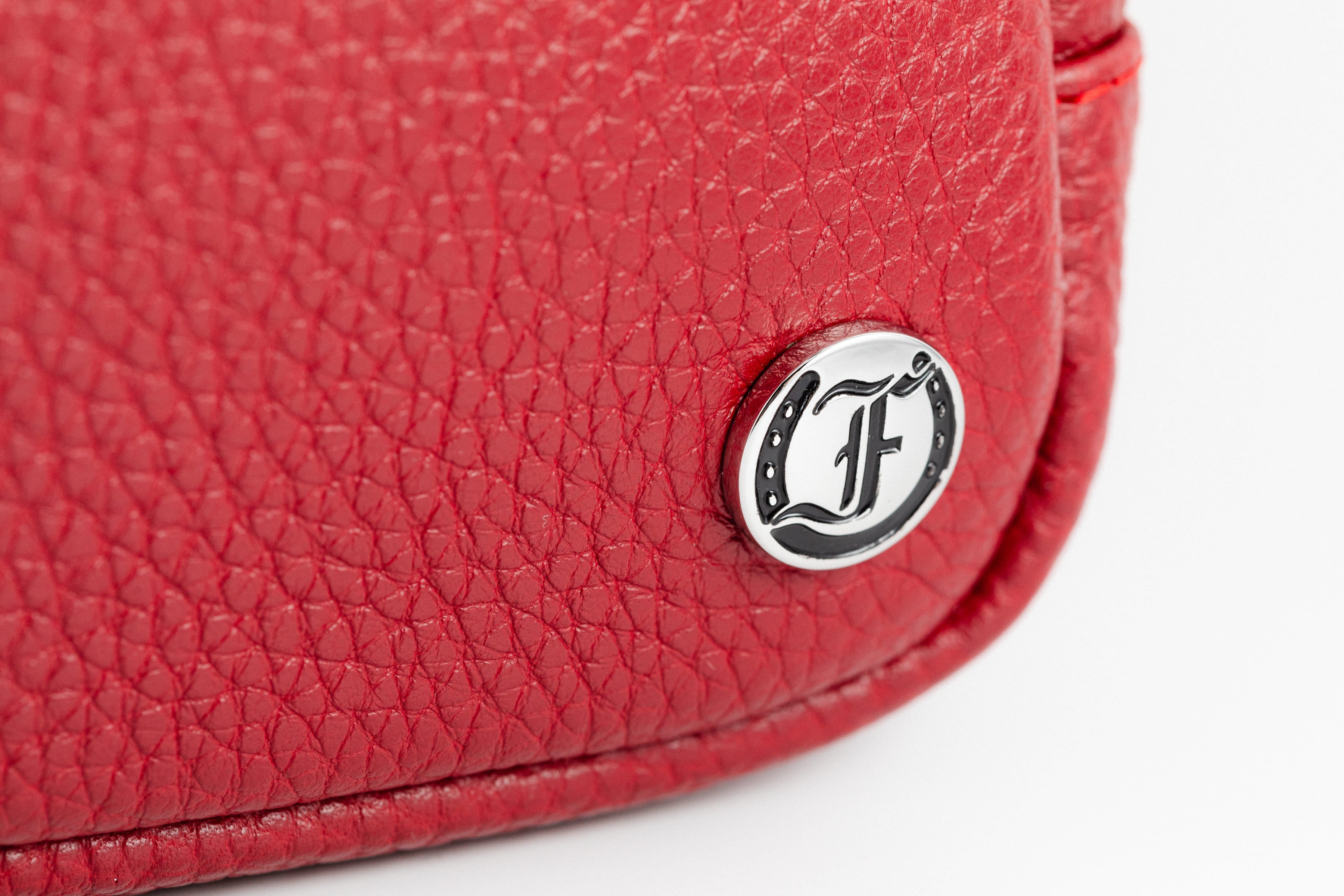 Close-up of Freedman's Norfolk Crossbody Bag in Red Leather, showing silver logo medallion on textured leather.