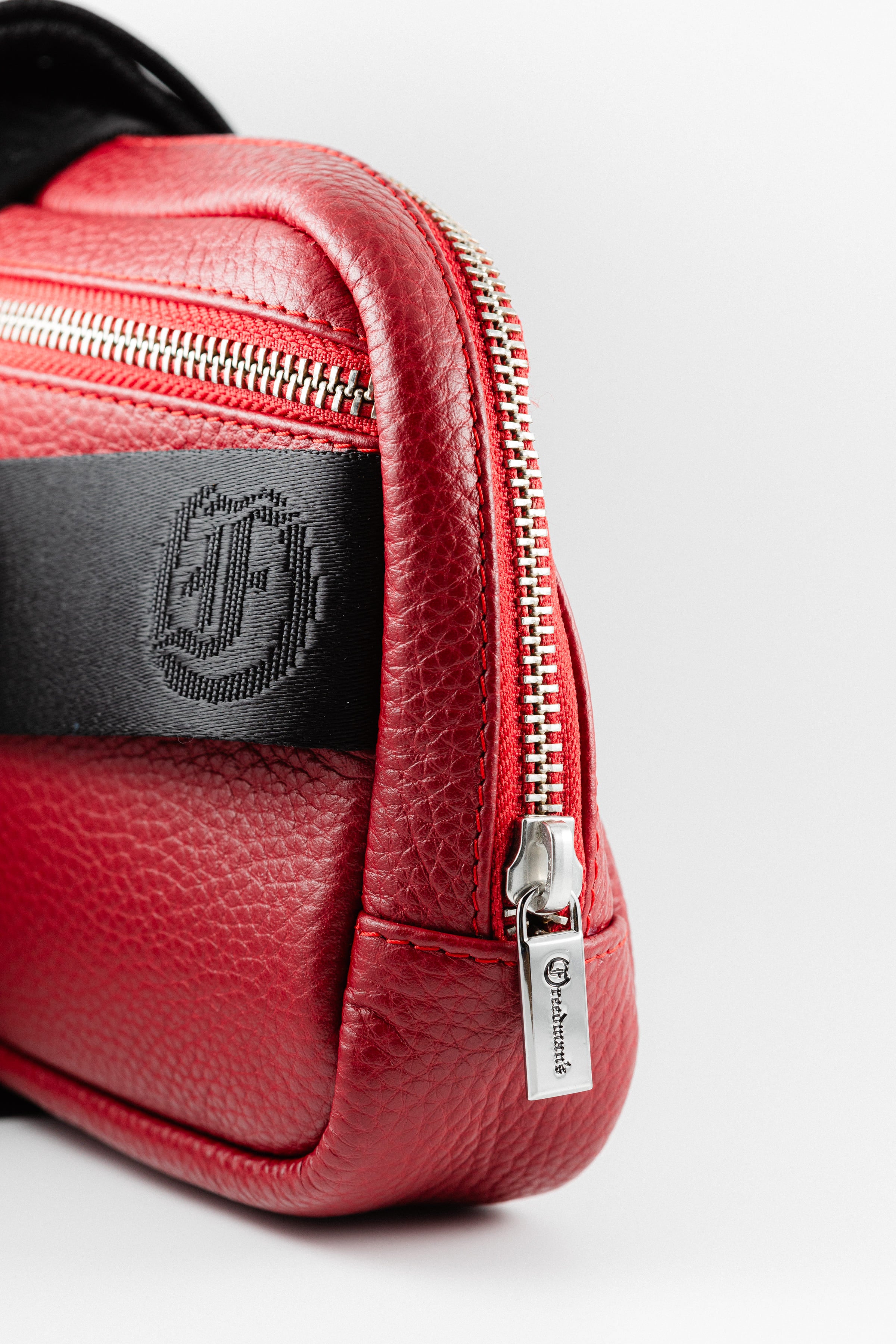 Close-up of Freedman's Norfolk Crossbody Bag in Red Leather, showing silver zipper, logo pull, and branded fabric strap.