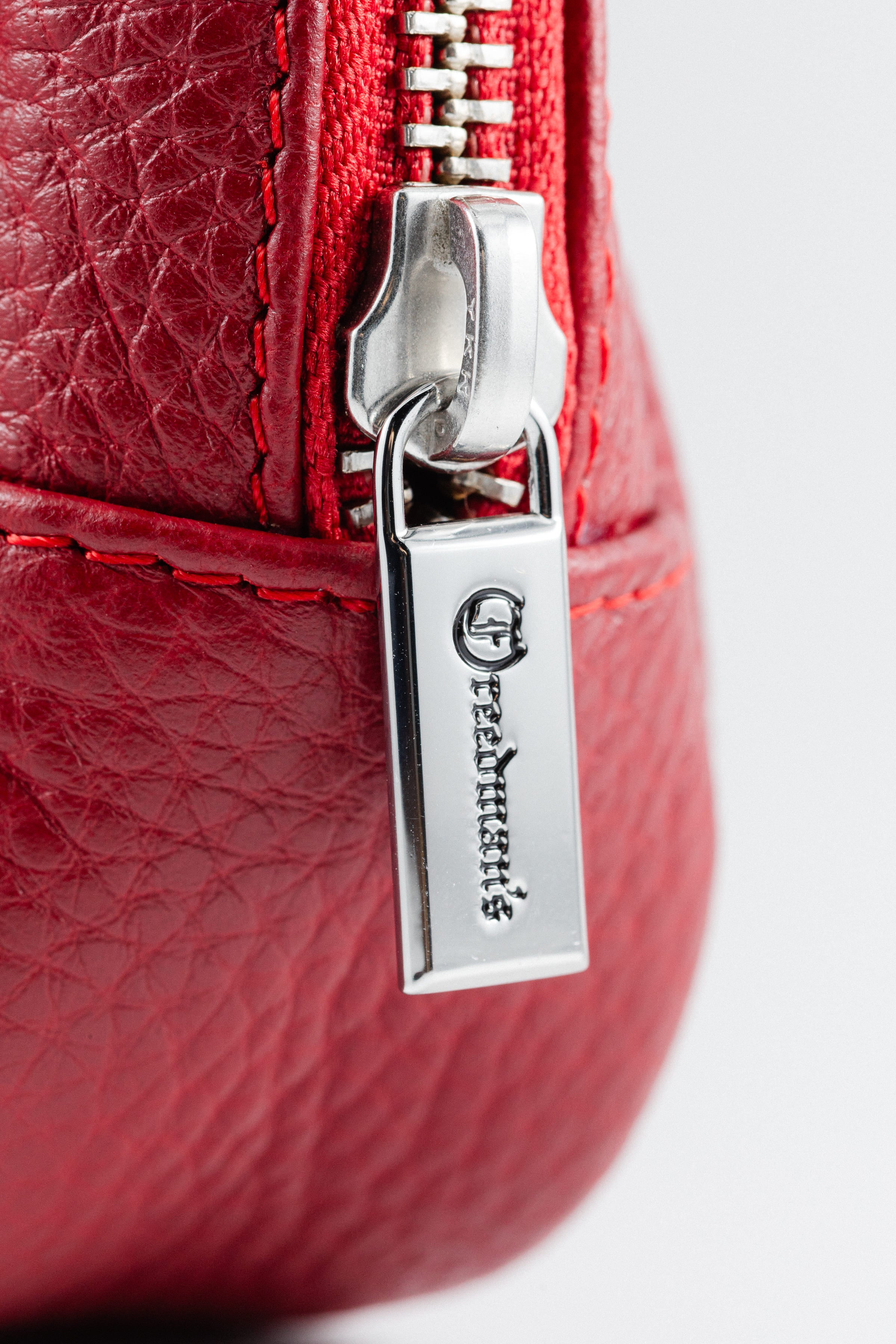 Close-up of Freedman's Norfolk Crossbody Bag in Red Leather, showing silver zipper, logo pull, and branded fabric strap.