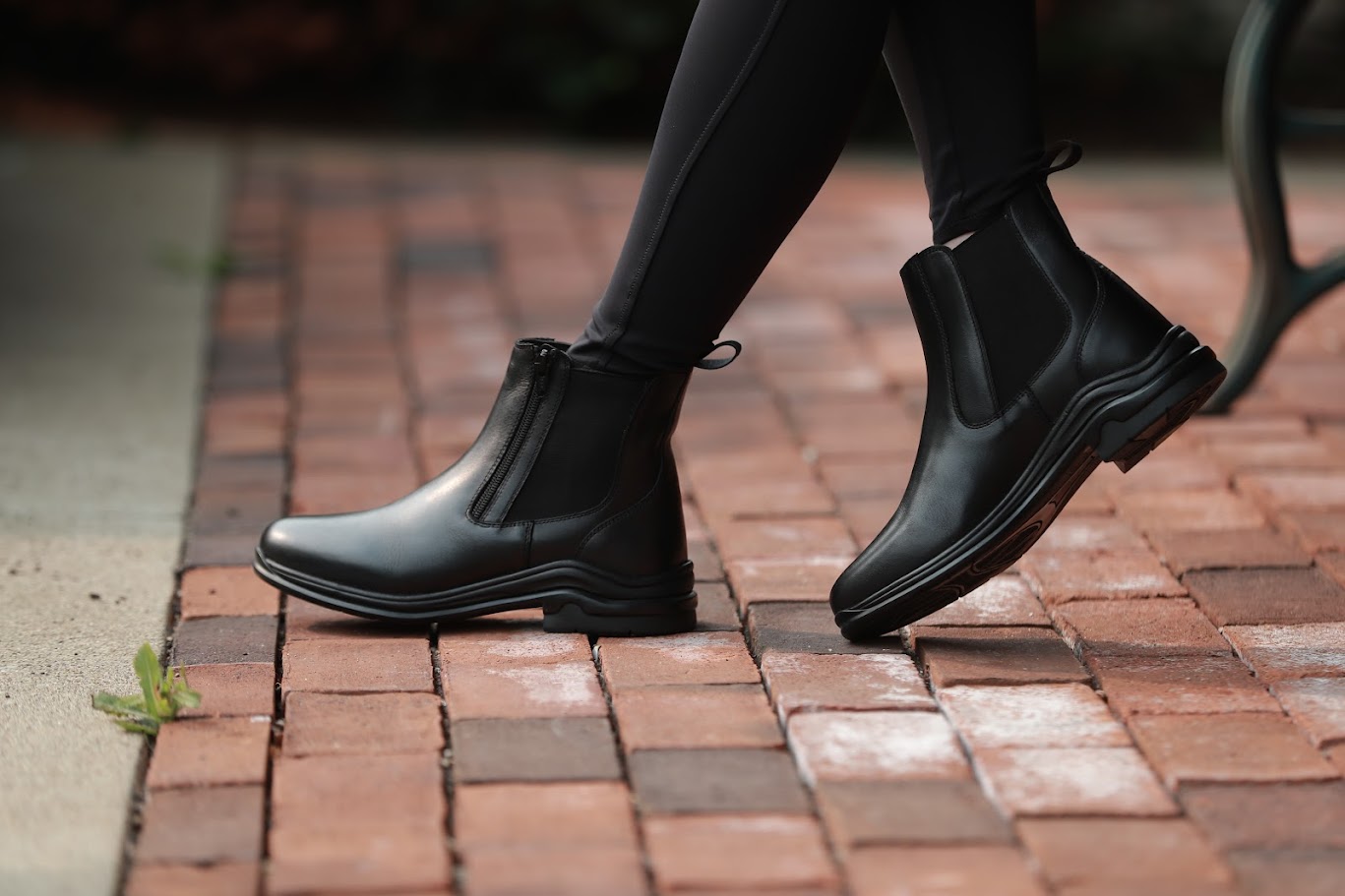 Pisgah Jodhpur Boots in black leather, worn by a person walking on a brick path.
