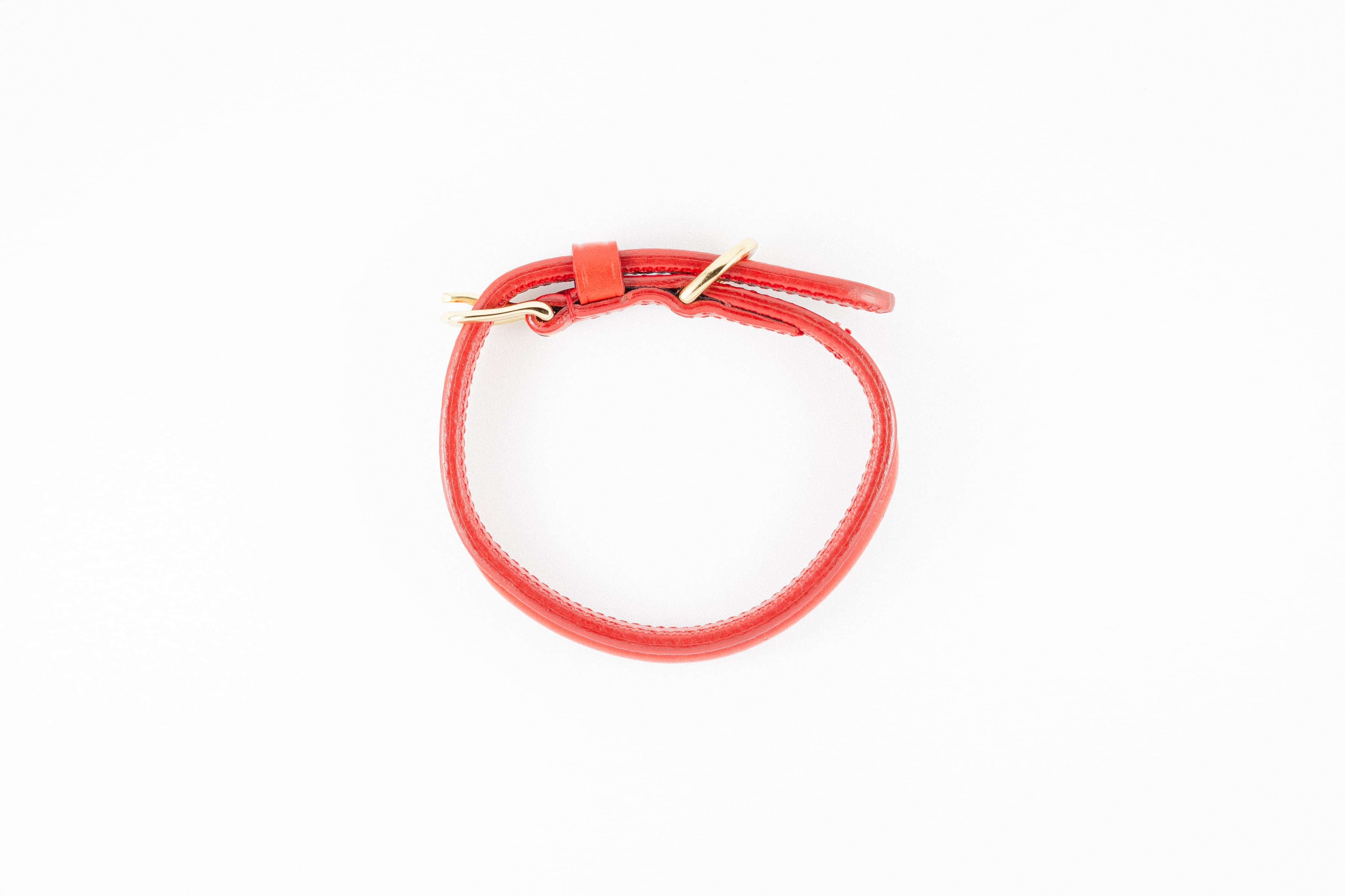 Red leather dog collar with gold hardware, shown from above on a white background.

