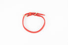 Red leather dog collar with gold hardware, shown from above on a white background.

