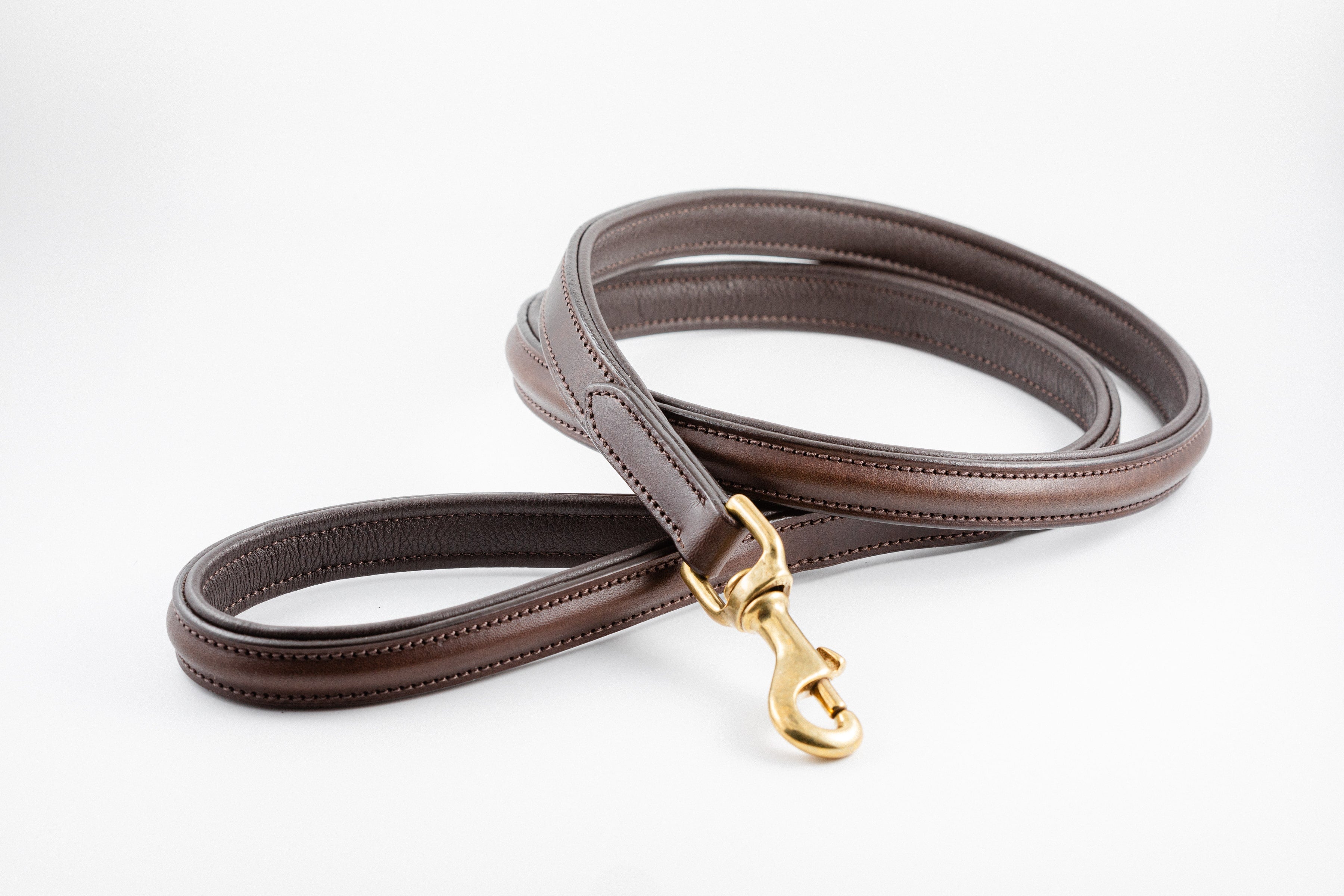 Brown leather Raised Dog Leash with gold clasp and stitched detailing, lying flat on a white background.


