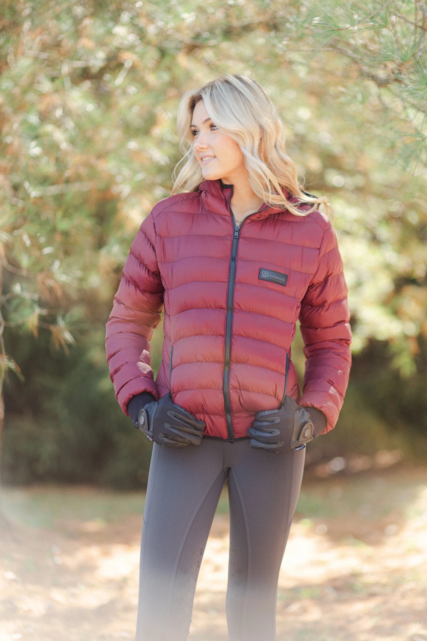 Woman wearing Signature Ladies' II Winter Gloves in black with a burgundy puffer jacket and riding pants while standing outdoors.