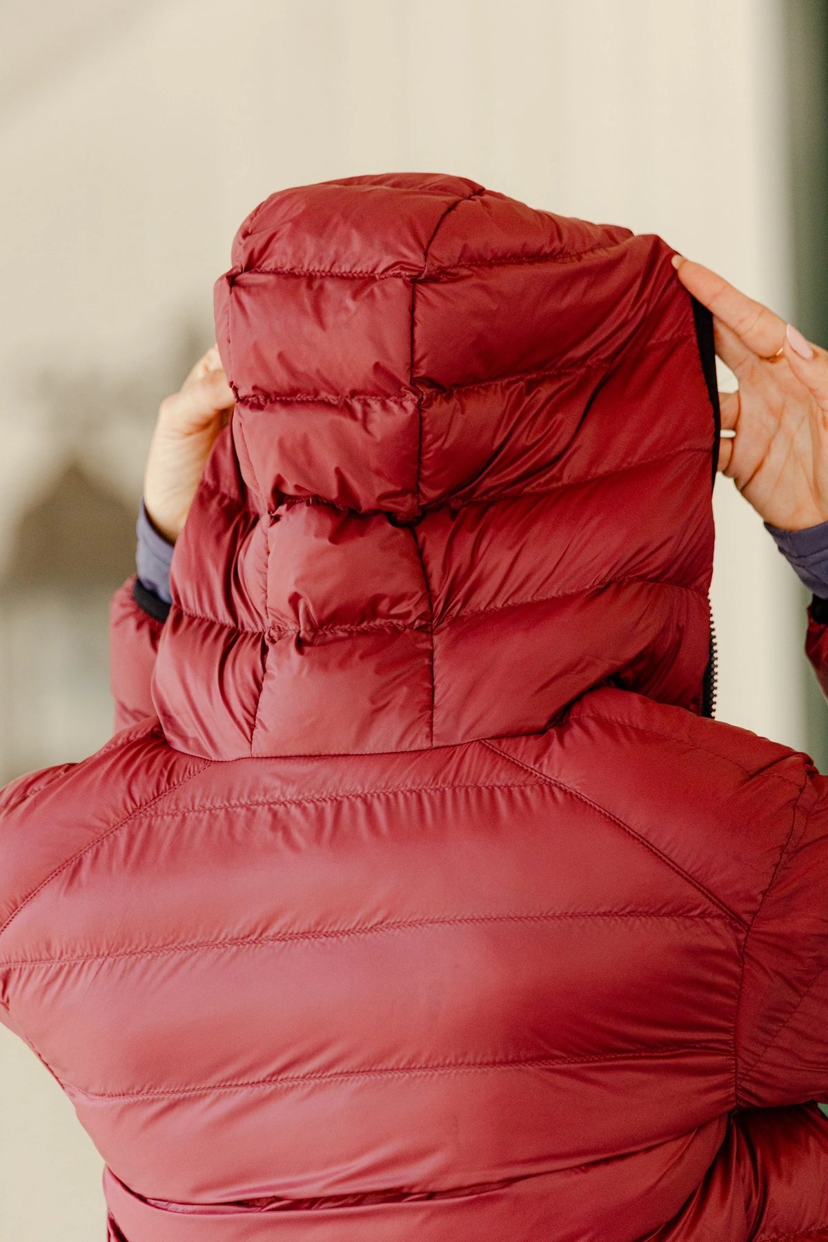 Back view of the Signature Ladies' Packable Puffer Jacket in burgundy, highlighting the quilted design and adjustable hood.