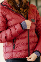 Close-up of the Signature Ladies' Packable Puffer Jacket in burgundy, highlighting the front zipper, quilted design, Freedman's logo patch, and zippered pockets.