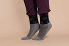 Two-tone gray and black socks with repeating circular Freedman's logo pattern, worn on feet with dark riding pants featuring visible texture and cuffs, light background.