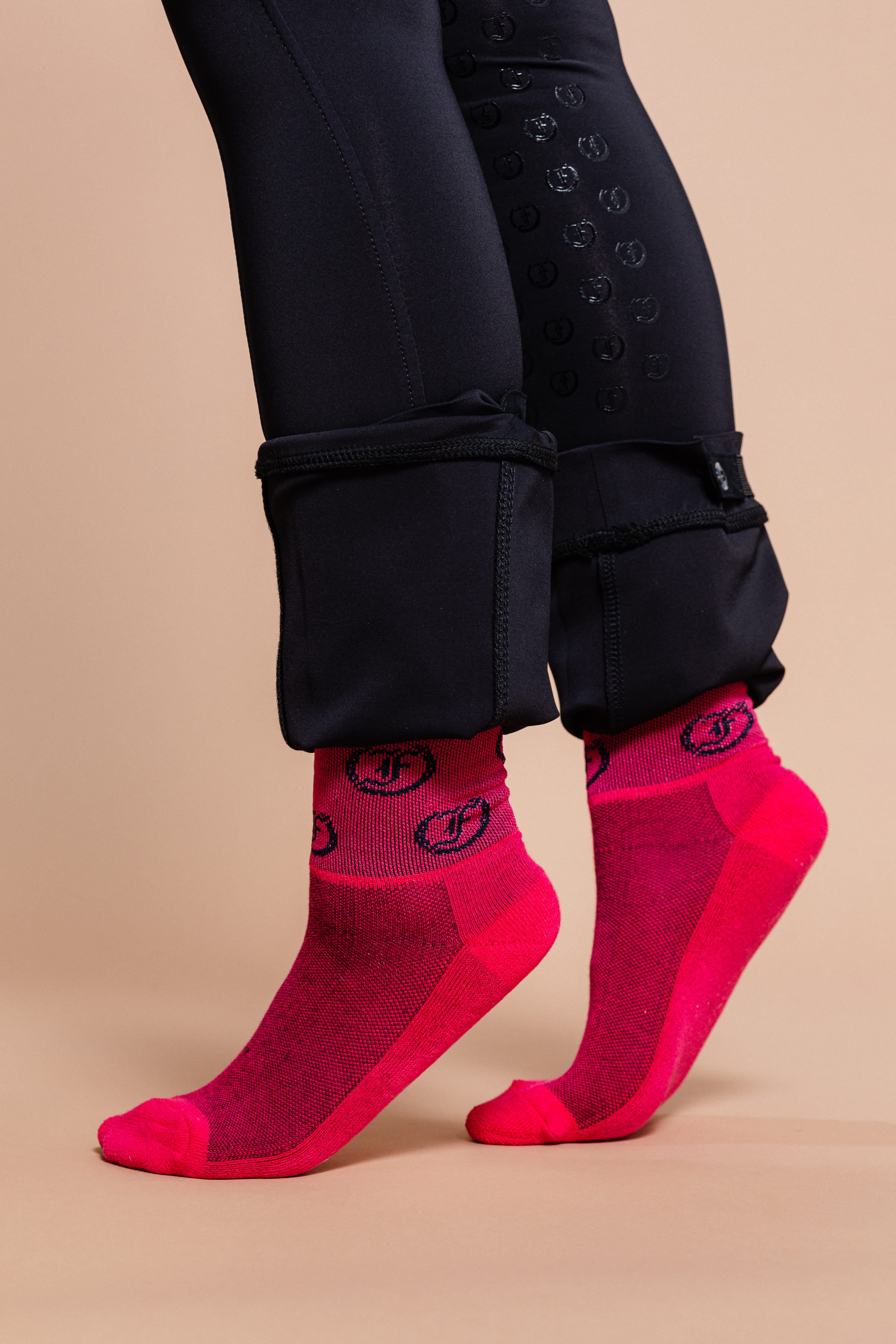 Pink socks with repeating Freedman's logo, worn on feet with dark riding pants and visible details.