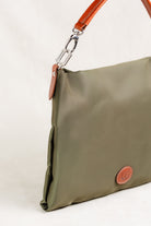 Freedman's Travois Bag in olive green, detailed side view showcasing the silver hardware connector, brown leather strap attachment, and the bag's structured side profile.
