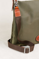 Freedman's Travois Bag in olive green, detailed view of the brown fabric strap, leather attachment with stitching, and silver adjustable buckle.