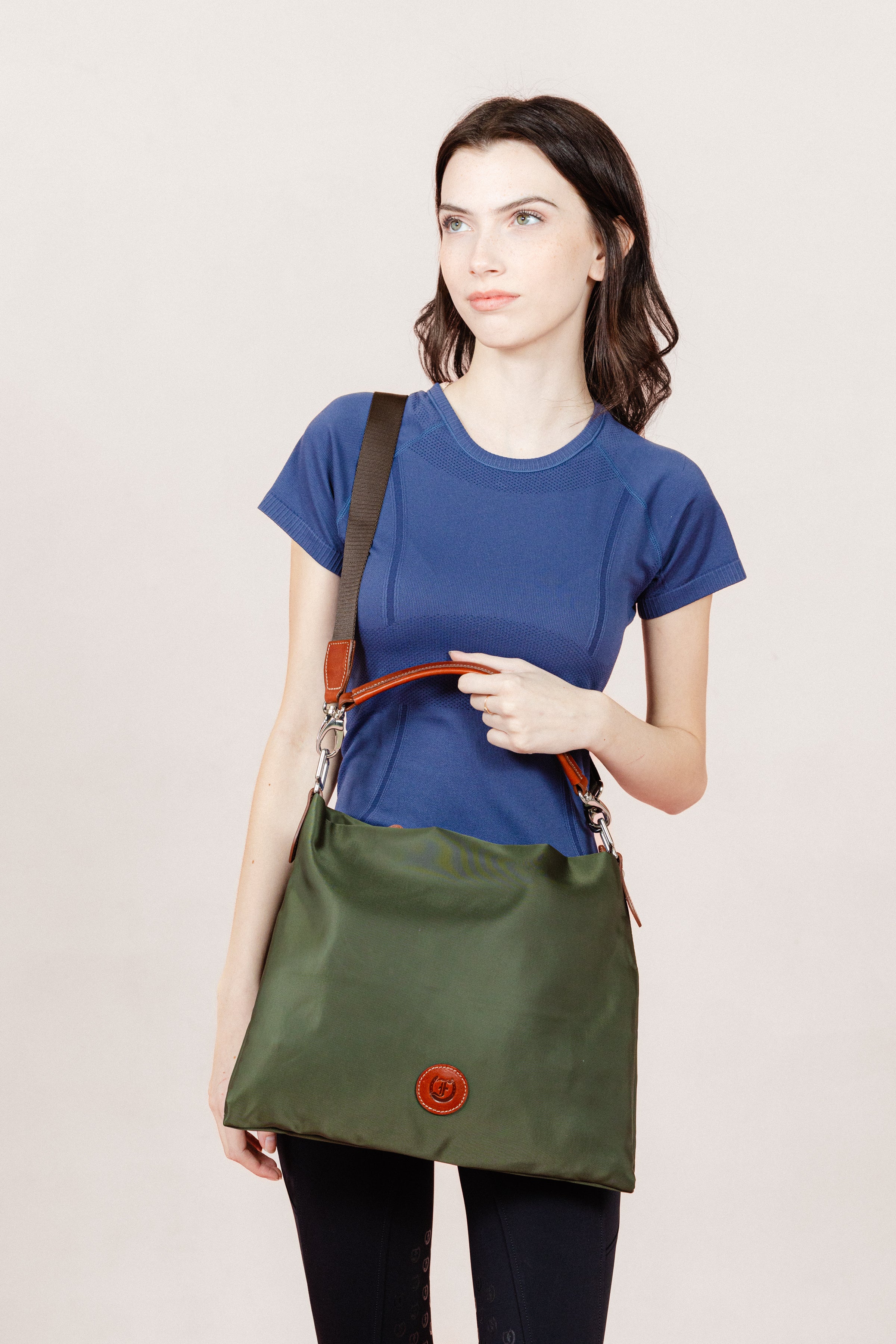Model showcasing the Travois Bag with a casual outfit of a blue t-shirt and black jods on a clean white backdrop.