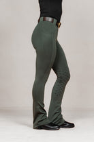 Side view of women's Umber Green jodhpurs by Freedman Harness, featuring full seat silicone grip, flared leg, and black riding boots – stylish and functional equestrian wear