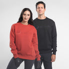 Man and woman wearing Freedman's embroidered crewneck sweatshirts in black and Brick Red. These stylish and cozy sweatshirts feature a tonal Freedman’s logo, perfect for casual wear and layering