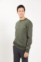 Man wearing Freedman's embroidered crewneck sweatshirts in Green Olive. These stylish and cozy sweatshirts feature a tonal Freedman’s logo, perfect for casual wear and layering