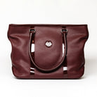 reedman's Victoria Tote, Burgundy textured leather, high gloss patent leather handles, silver circular logo on front, light contrast stitching, light background.