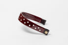 Burgundy Patent Leather Browband with white dots, wide tapered design, polished brass Freedman logo buttons, and dark leather ends, angled view.