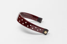 Burgundy Patent Leather Browband with small white dots, wide tapered design, polished brass Freedman logo buttons, and dark leather ends, angled view.