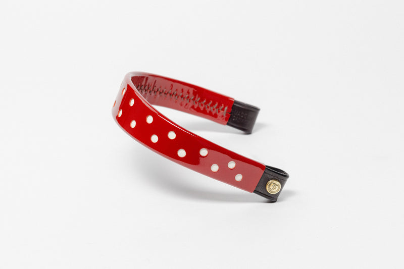 Red browband with white dots, wide tapered design, polished brass Freedman logo buttons, and dark leather ends.