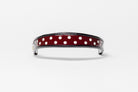 Burgundy and white dot patent leather browband, wide tapered design, turned edge, dark leather ends with gold button, shown flat.