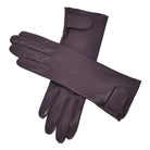  The Yorkville Show Glove, brown leather gloves crossed, with wrist strap and button detail, visible seam stitching, light background.