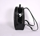 Black leather backpack, The Jaunty by Freedman's, side profile with patent leather panel, zippers, and shoulder straps.