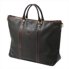 Freedman's Victoria Tote Large, dark textured leather, brown leather trim along edges and center straps, embossed circular logo on front, light contrast stitching, dual rolled handles with metal hardware, light background.