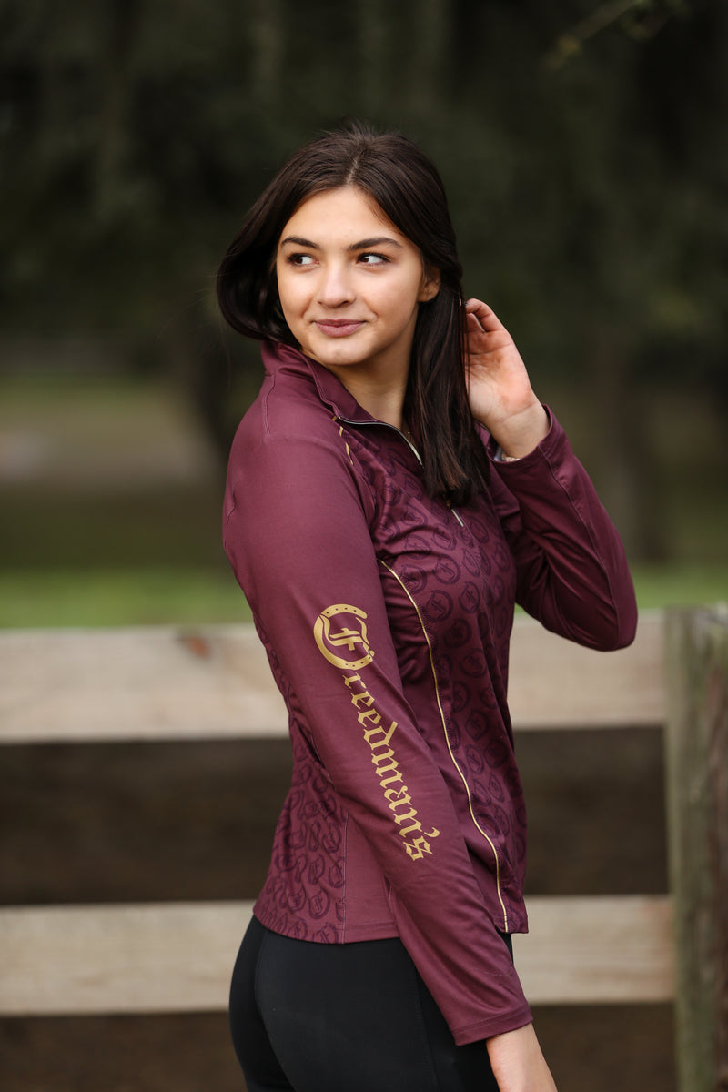 Echo 1/4 Zip Long Sleeve Shirt in deep burgundy with gold Freedman’s logo printed on the left sleeve. Stylish, high-performance equestrian apparel with a sleek design and subtle pattern.