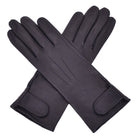  The Yorkville Show Glove, black leather gloves crossed, with wrist strap and button detail, visible seam stitching, light background.
