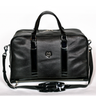 Freedman's Grand Break Duffel Bag, black textured leather, silver hardware, embossed logo, patent leather center straps, dual rolled handles, detachable shoulder strap with padded section, zipper closure, white background.