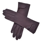  The Yorkville Show Glove, brown leather gloves crossed, with wrist strap and button detail, visible seam stitching, light background.