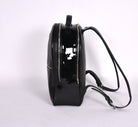 Black leather backpack, The Jaunty by Freedman's, side profile with patent leather panel, zippers, and shoulder straps.
