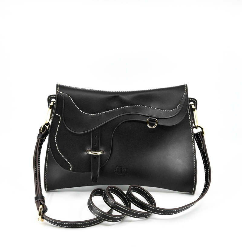 Black leather shoulder bag, The Trooper by Freedman's, with saddle flap detail, silver hardware, and light stitching.