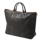 Freedman's Victoria Tote Large, dark textured leather, brown leather trim along edges and center straps, embossed circular logo on front, light contrast stitching, dual rolled handles with metal hardware, light background.
